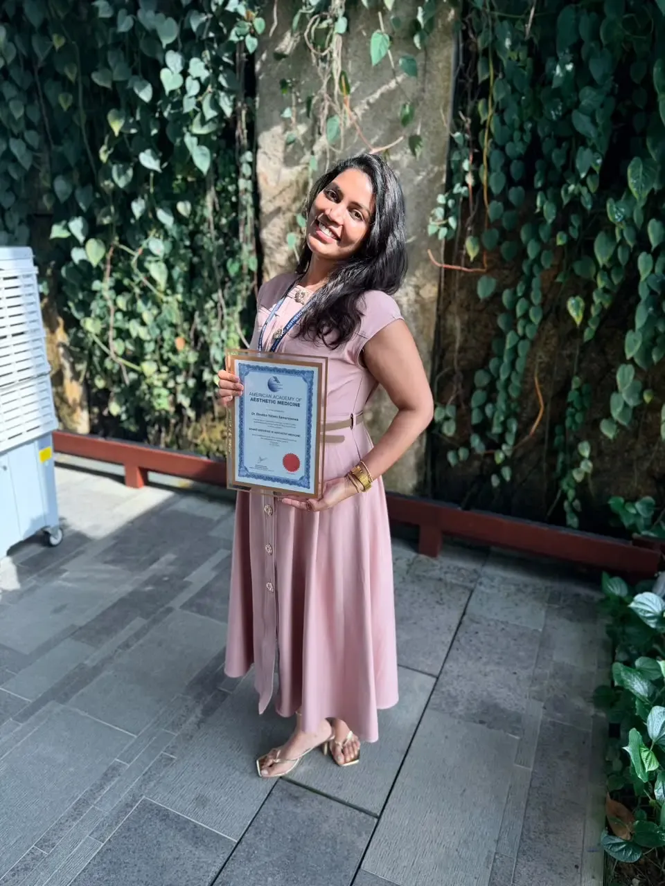 Dr Dinelka Yohani Samarajeewa holding her American Academy of Aesthetic Medicine Level 3 board certification certificate in Singapore, July 2026